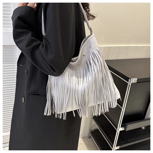 Detail of grey suede shoulder bag with long fringes and metal rivet reinforcement