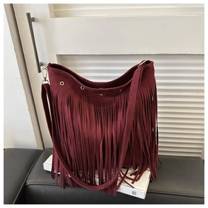 Detailed close-up of dark red suede tassel crossbody bag with golden metal ring