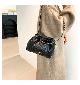 Close-up of quilted black crossbody bag with gold chain strap and elegant metallic detail