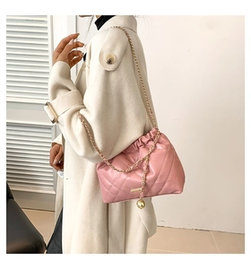Close-up of pink quilted cloud bag with gold chain strap and metal ball detail