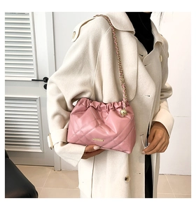 Detailed close-up of pink quilted chain strap bag on model wearing a beige coat