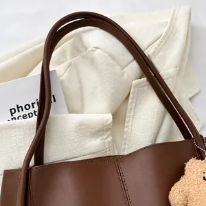 Detail of comfortable brown leather shoulder straps and cute plush bear charm on a tote bag