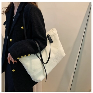 Detail einer weichen weißen Plüschtasche mit schwarzen Trägern auf Tweed-Jacke
