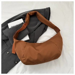Detail shot of caramel nylon crescent bag with quilted shoulder strap on grey blazer
