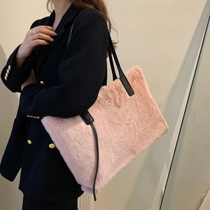 Rosa Plüsch-Tragetasche mit schwarzem Riemen, getragen von einer Frau im schwarzen Blazer
