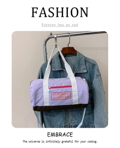 Detail der lila Nylon-Reisetasche mit kontrastierenden Webgriffen und roter Tasche