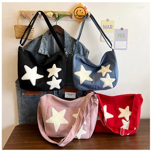 Detailed view of canvas tote bags in four colors with plush star patches and adjustable strap