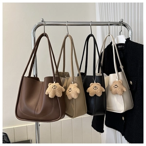 Row of minimalist tote bags in brown, camel, black and white with cute plush bear charms