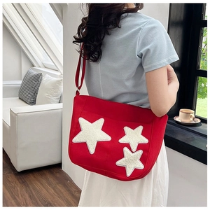 Detail of red canvas tote bag featuring three shimmering white sequin star patches