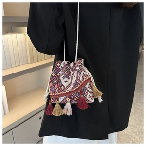 Ethnic woven bucket bag with vibrant geometric patterns and colorful side tassels