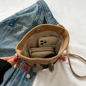 Detail view of ethnic canvas crossbody bag interior with phone and colorful tassels