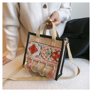 Detail view of ethnic floral embroidery and tassel on beige canvas tote bag