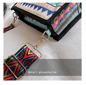 Detail of embroidered ethnic crossbody bag with colorful woven strap and metal hooks