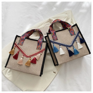 Détail de sacs seaux en lin bohème avec poignées tissées colorées et glands à pompons