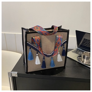 Détail du sac seau en lin avec pompons dégradés bleus et bandoulière ethnique