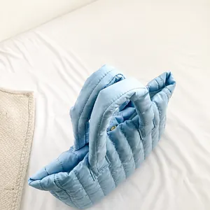 Detail of light blue quilted puffer tote bag with soft padded handle and nylon texture