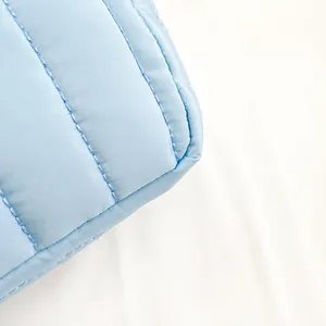 Detailed macro view of light blue quilted nylon fabric with premium stitching craftsmanship