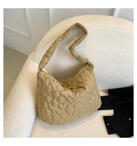 Detailansicht des Blumen-Steppmusters der beigen Nylon-Tasche auf einem weißen Sofa