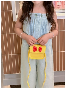 Vue détaillée du petit sac bandoulière jaune pour fille avec nœud rouge et coutures