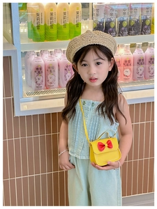 Mini sac bandoulière jaune pour fille avec un gros nœud rouge porté par un mannequin