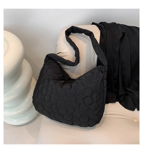 Detailaufnahme der schwarzen gesteppten Nylon-Einkaufstasche mit floralem Muster auf Sofa