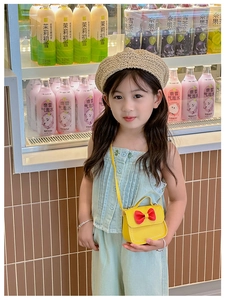 Détail d'un sac jaune pour fille avec nœud rouge porté par une petite fille