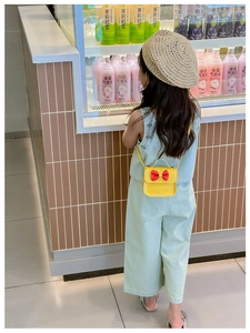 Détail d'une tenue d'enfant en denim bleu clair avec un sac à bandoulière jaune à nœud