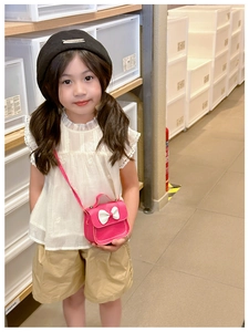 Détail d'une fille portant le mini sac bandoulière rose foncé orné d'un nœud blanc