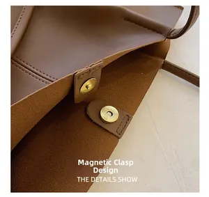 Detail of brown leather tote featuring a golden magnetic clasp and precise stitching