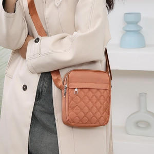 Bolso bandolera de nailon acolchado naranja con correa ajustable mostrado en un modelo