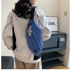 Detail view of the blue sports crossbody bag with a checkered bear charm and nylon texture