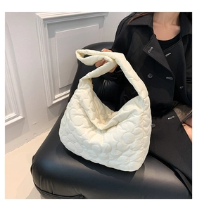 Detail der cremeweißen gesteppten Puffer-Tasche mit Blumenmuster und weicher Textur