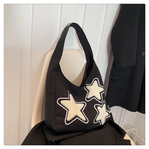 Detalle del bolso tote negro con parches de estrellas blancas y etiqueta de moda