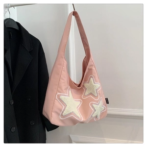 Detalle del bolso de lona rosa con tres parches de estrellas y etiqueta lateral