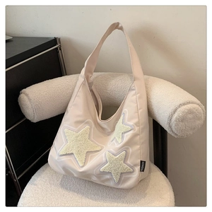 Detalle del bolso tote de lona beige con estrellas de peluche y etiqueta FASHION