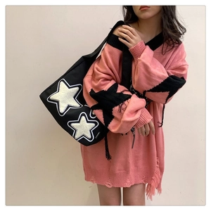 Detalle de un bolso tote de lona negra con estrellas de felpa blancas y etiqueta moda
