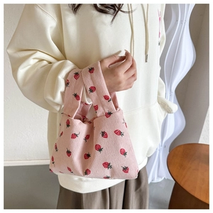 Pink corduroy mini tote bag featuring cute red strawberry patterns held by a model