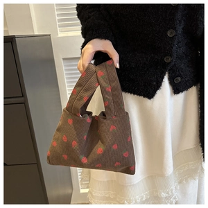 Detail of brown corduroy mini tote bag with cute strawberry pattern held by model