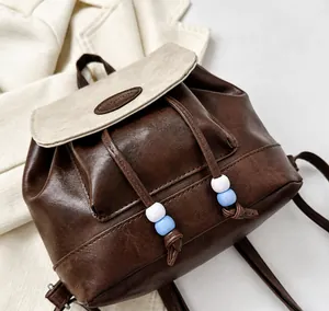 Detailed close-up of retro brown PU leather backpack with beige flap and beaded drawstring