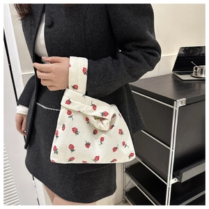 Detail of cute corduroy tote bag with strawberry pattern held by model in office