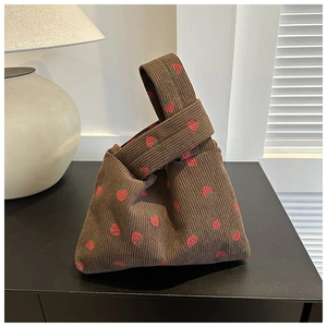 Detail of cute brown corduroy tote bag with strawberry print and knotted handle