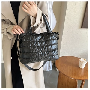 Gros plan d'un sac cabas matelassé noir porté par un mannequin dans un café chic