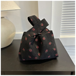 Detail view of black corduroy knot bag with red strawberry print pattern and fabric texture