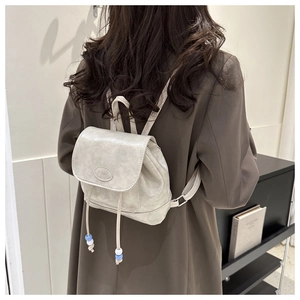 Close-up of pearl white PU leather backpack with drawstring and blue bead accents