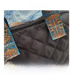 Detail of black quilted tote bag featuring a colorful bohemian style printed strap