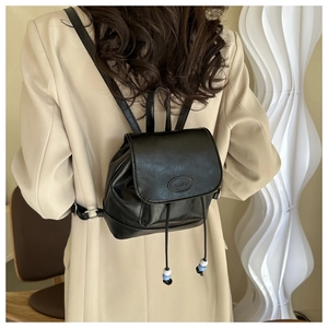 Rear view of a black mini leather backpack with drawstring beads on a model