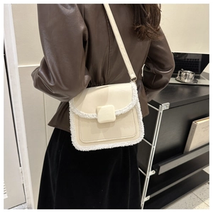 Detail view of cream leather crossbody bag with white faux fur trim on model