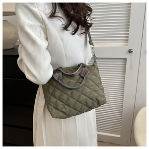 Detail of olive green quilted bag with ethnic pattern strap and rhombic stitching