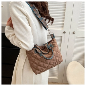 Close-up of brown quilted shoulder bag with bohemian ethnic patterned strap detail