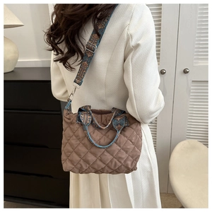 Side view of a brown quilted puffer bag with a colorful ethnic patterned wide shoulder strap